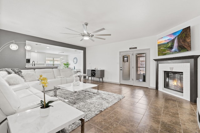 living room with ceiling fan, a fireplace, and sink