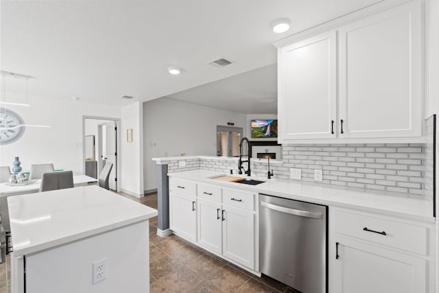 kitchen with dishwasher, sink, a kitchen island, and white cabinets