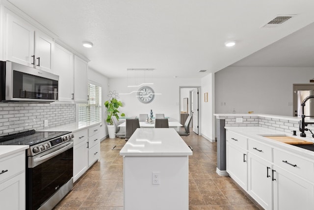 kitchen featuring a kitchen island, white cabinetry, appliances with stainless steel finishes, and sink