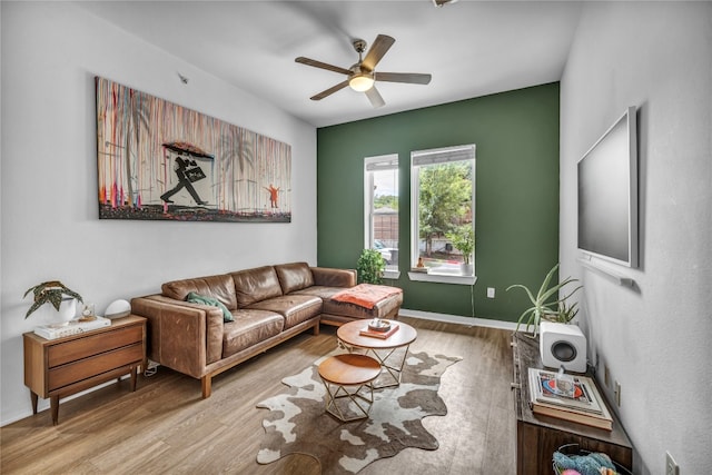 living room featuring a ceiling fan, baseboards, and wood finished floors