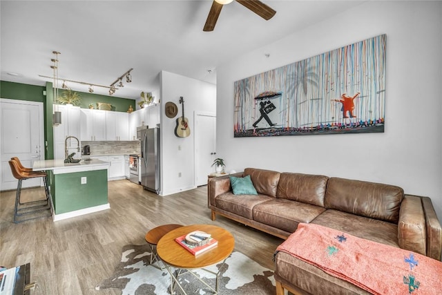 living room featuring sink, light hardwood / wood-style floors, and ceiling fan