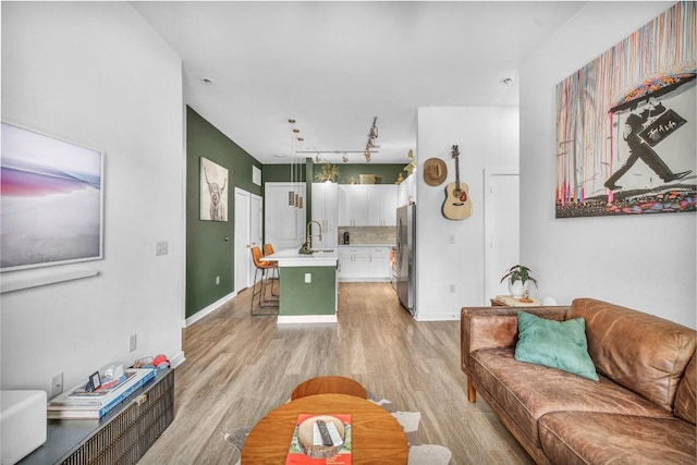 living room featuring rail lighting, sink, and light wood-type flooring