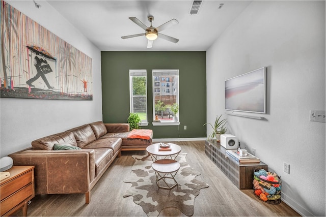 living room with baseboards, a ceiling fan, visible vents, and wood finished floors