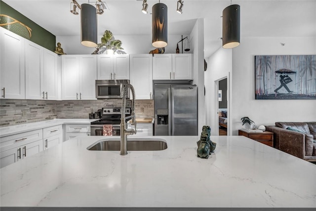 kitchen with tasteful backsplash, white cabinets, hanging light fixtures, stainless steel appliances, and light stone countertops