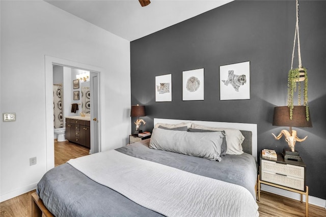 bedroom with ensuite bath and light wood-type flooring