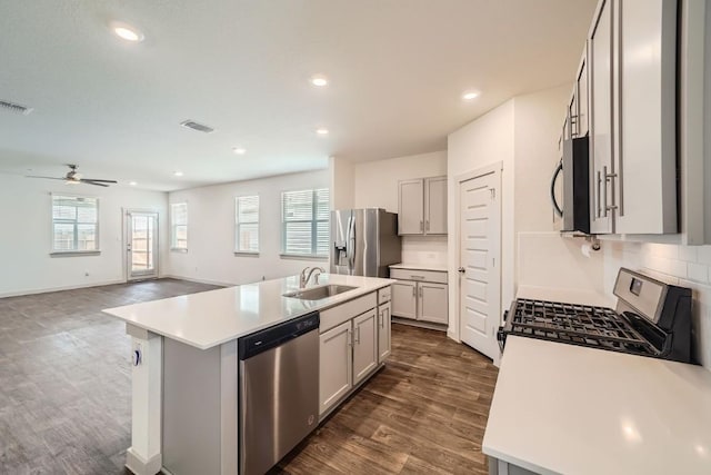 kitchen with stainless steel appliances, sink, a center island with sink, and backsplash