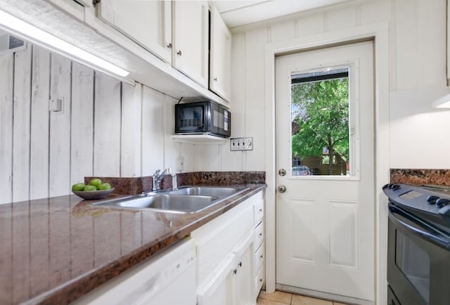 kitchen featuring sink, dark stone countertops, white cabinets, range, and light tile patterned floors