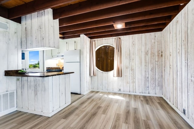 kitchen with wood walls, light hardwood / wood-style flooring, white fridge, beamed ceiling, and white cabinets