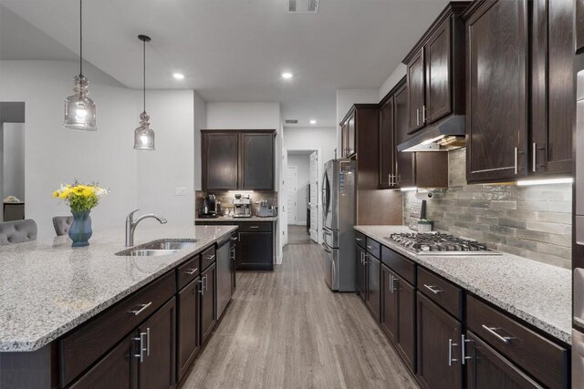 kitchen featuring dark brown cabinetry, sink, hanging light fixtures, light hardwood / wood-style flooring, and appliances with stainless steel finishes