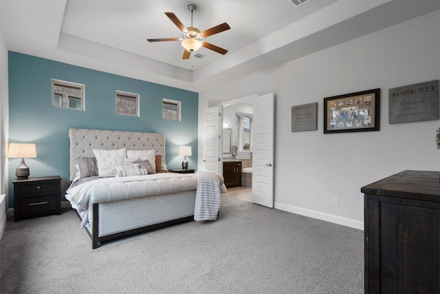 carpeted bedroom featuring ceiling fan, ensuite bath, and a tray ceiling