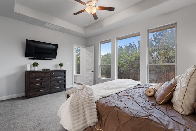 carpeted bedroom featuring a raised ceiling and ceiling fan