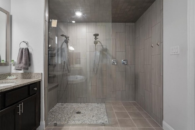 bathroom with a tile shower, vanity, and tile patterned flooring