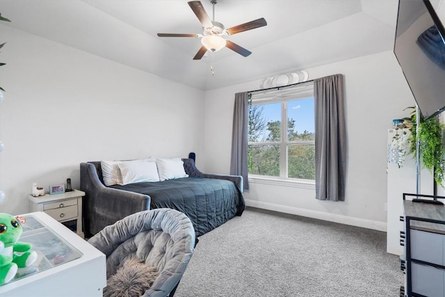 bedroom featuring ceiling fan, a tray ceiling, and carpet floors