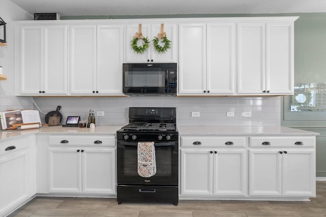 kitchen with tasteful backsplash, white cabinets, light stone counters, and black appliances