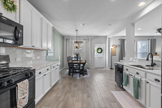 kitchen featuring white cabinetry, sink, pendant lighting, and black appliances