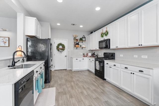 kitchen with sink, white cabinets, backsplash, and black appliances