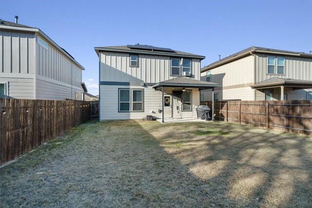 back of property featuring a lawn, a patio, and solar panels