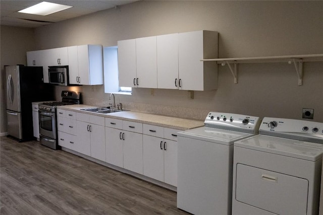 laundry area featuring wood-type flooring, separate washer and dryer, and sink