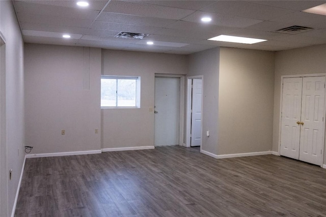 empty room featuring a paneled ceiling and dark hardwood / wood-style floors