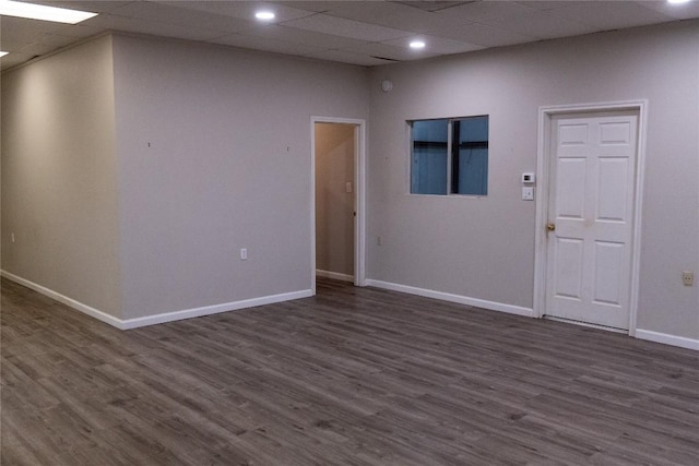 spare room with dark wood-type flooring and a drop ceiling