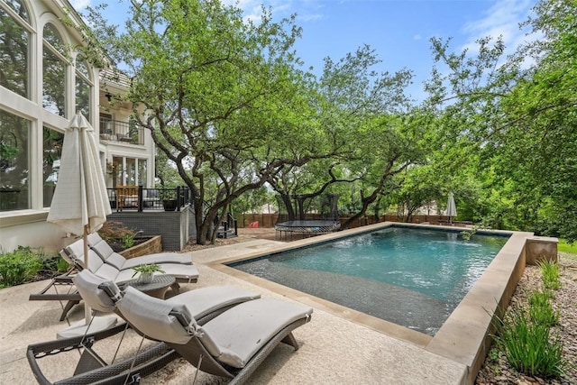 view of swimming pool featuring a patio, pool water feature, and a trampoline