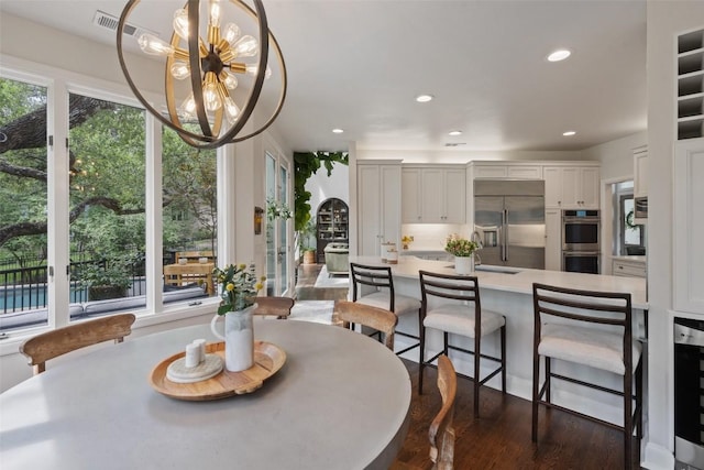 dining room with dark wood-type flooring, a notable chandelier, and beverage cooler