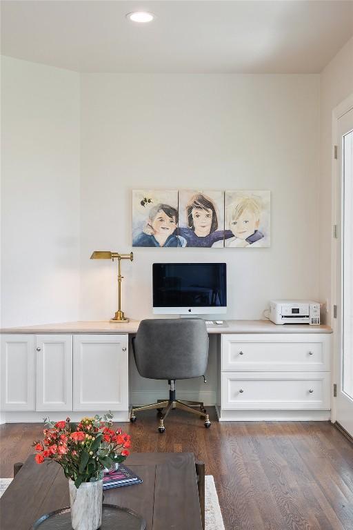 home office with dark wood-type flooring and built in desk