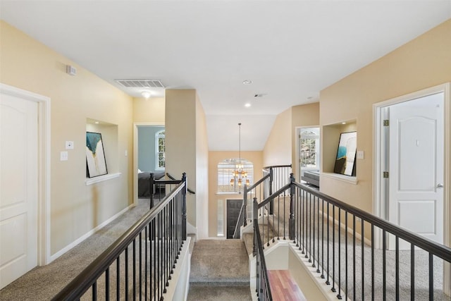 corridor with vaulted ceiling, carpet, and a chandelier