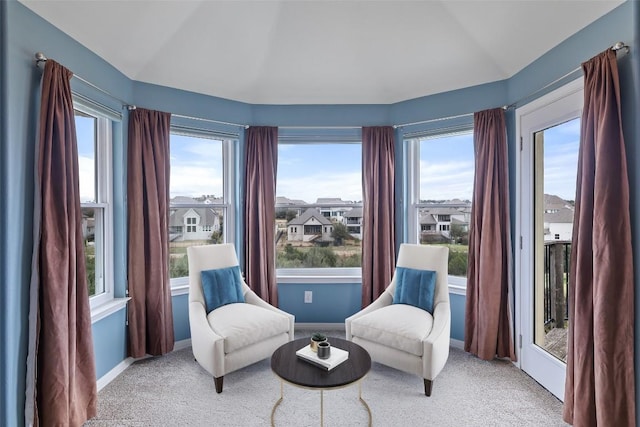 living area with vaulted ceiling, a healthy amount of sunlight, and light carpet