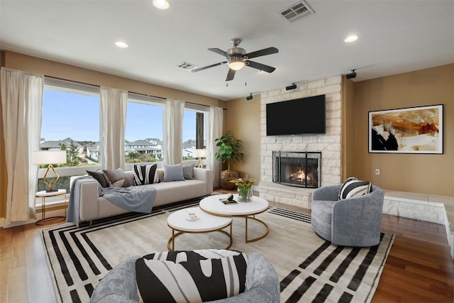 living room with ceiling fan, a fireplace, and wood-type flooring