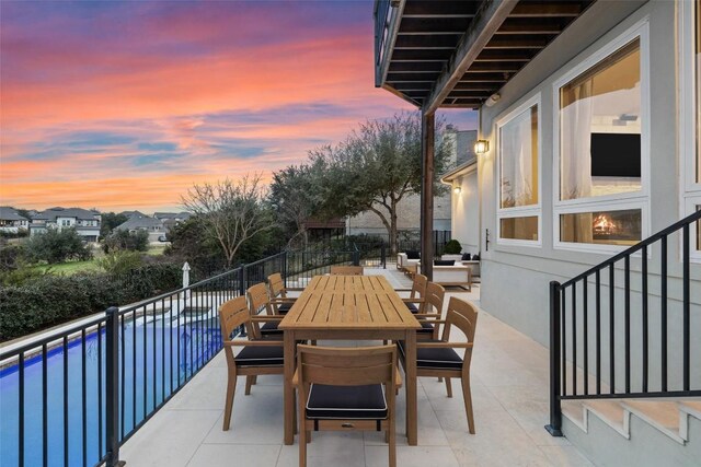 patio terrace at dusk featuring a balcony