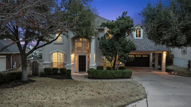 view of front of home with an attached garage, driveway, stone siding, and roof with shingles