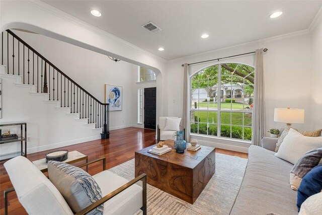 living area with wood finished floors, visible vents, stairs, and ornamental molding