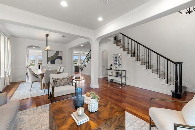 living room with stairway, arched walkways, wood-type flooring, baseboards, and visible vents