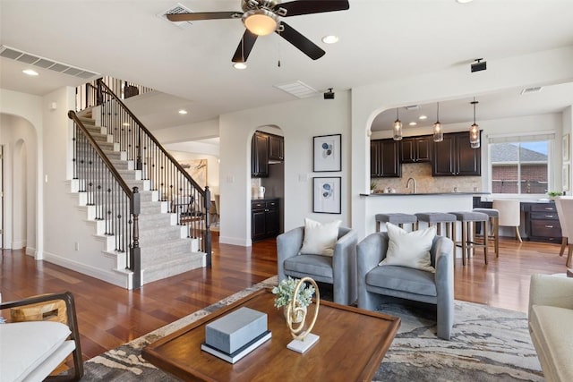 living room featuring arched walkways, wood finished floors, visible vents, and ceiling fan
