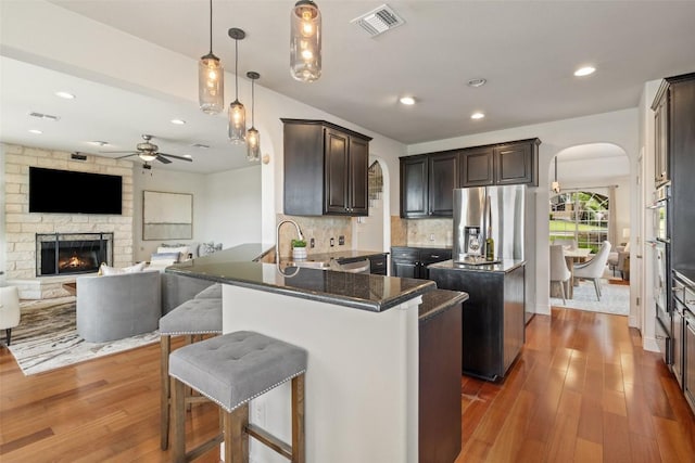 kitchen featuring a center island, visible vents, arched walkways, and ceiling fan