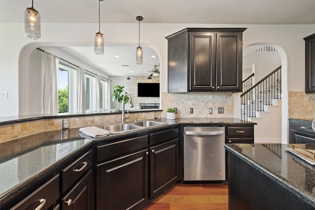 kitchen with arched walkways, backsplash, dishwasher, and a sink
