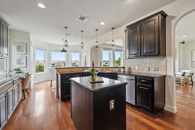 kitchen featuring dishwasher, visible vents, arched walkways, a center island, and a peninsula