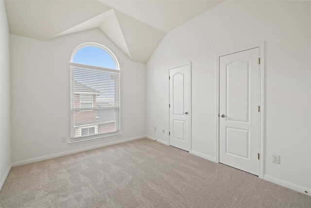 unfurnished bedroom featuring vaulted ceiling, carpet flooring, baseboards, and multiple windows