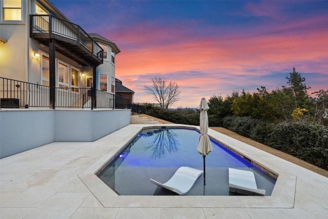 pool at dusk with an outdoor pool, central air condition unit, and a patio