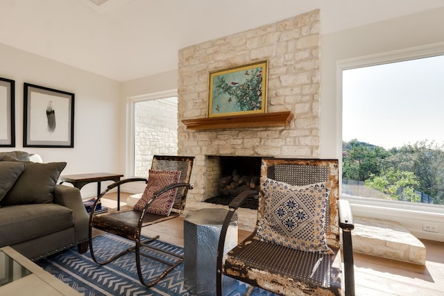 sitting room with a stone fireplace and hardwood / wood-style floors