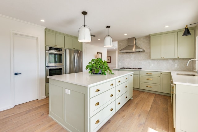 kitchen with sink, light hardwood / wood-style flooring, appliances with stainless steel finishes, a center island, and wall chimney exhaust hood