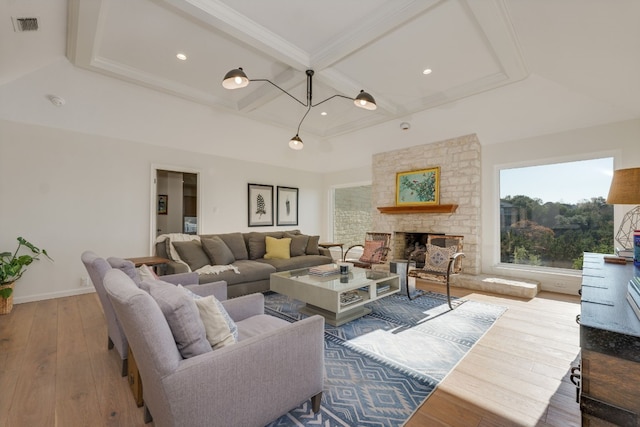 living room with a stone fireplace, beamed ceiling, wood-type flooring, coffered ceiling, and crown molding