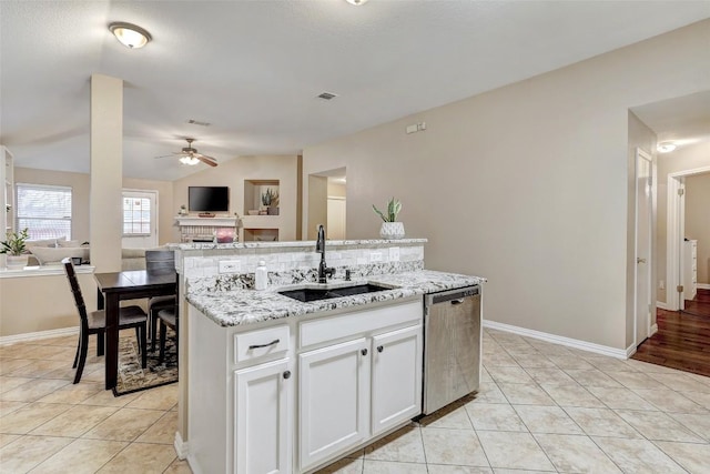 kitchen with light tile patterned flooring, sink, stainless steel dishwasher, a kitchen island with sink, and white cabinets