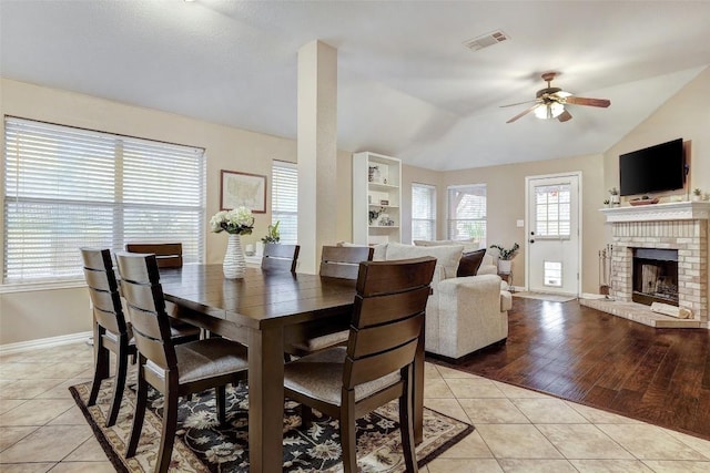 dining room with light tile patterned flooring, lofted ceiling, plenty of natural light, and a fireplace