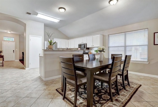 tiled dining space featuring vaulted ceiling