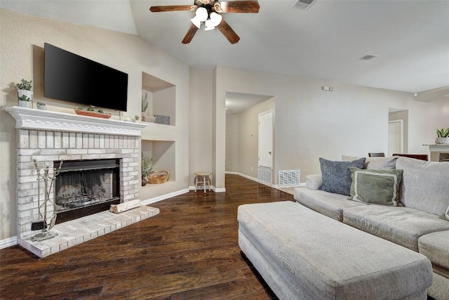 living room with dark wood-type flooring, ceiling fan, and a brick fireplace