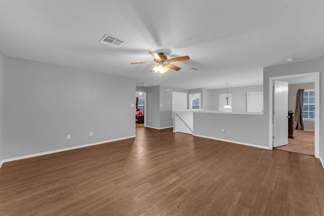 unfurnished living room featuring dark wood-type flooring and ceiling fan