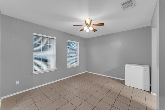 tiled empty room featuring ceiling fan