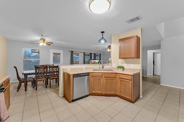 kitchen featuring pendant lighting, sink, stainless steel dishwasher, light tile patterned floors, and kitchen peninsula